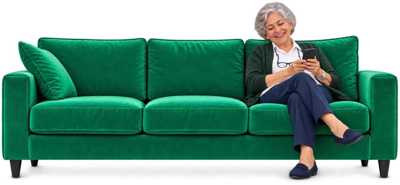 Imagen ilustrativa: pensionada sentada en un sofá verde sonríe mirando su celular