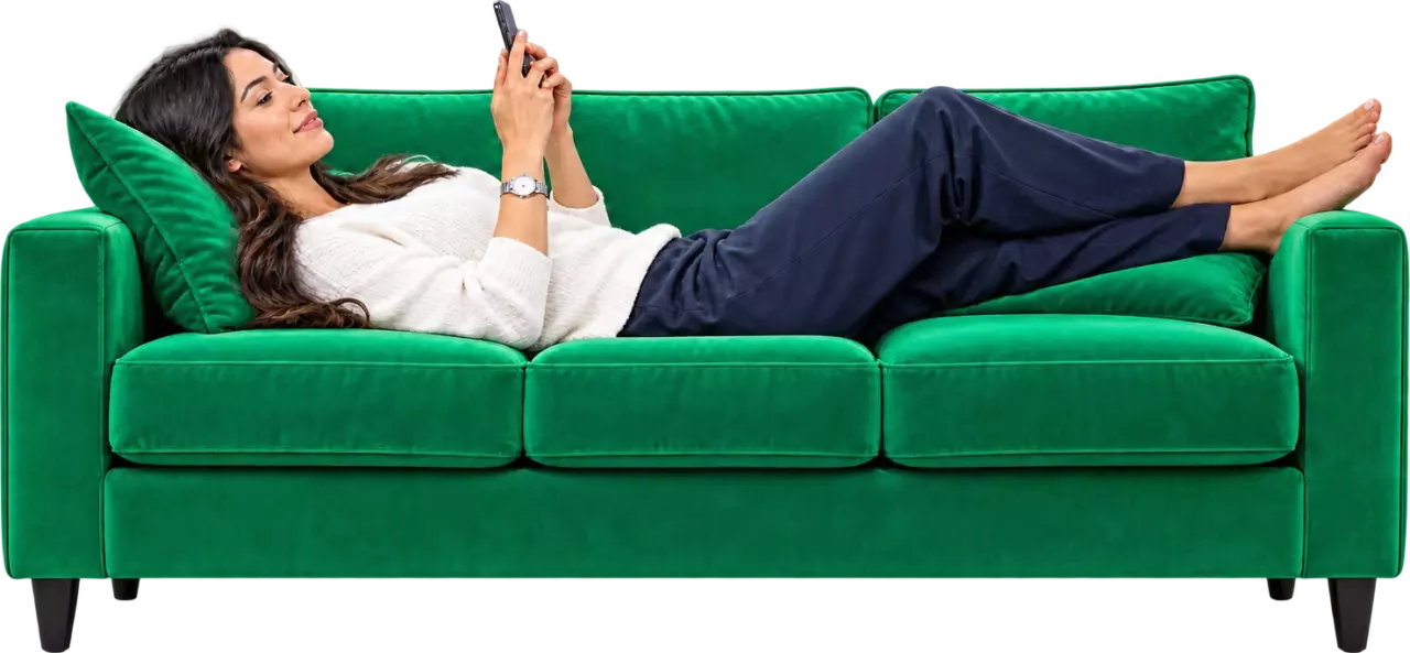 Mujer recostada en un sofá verde mira su celular con tranquilidad